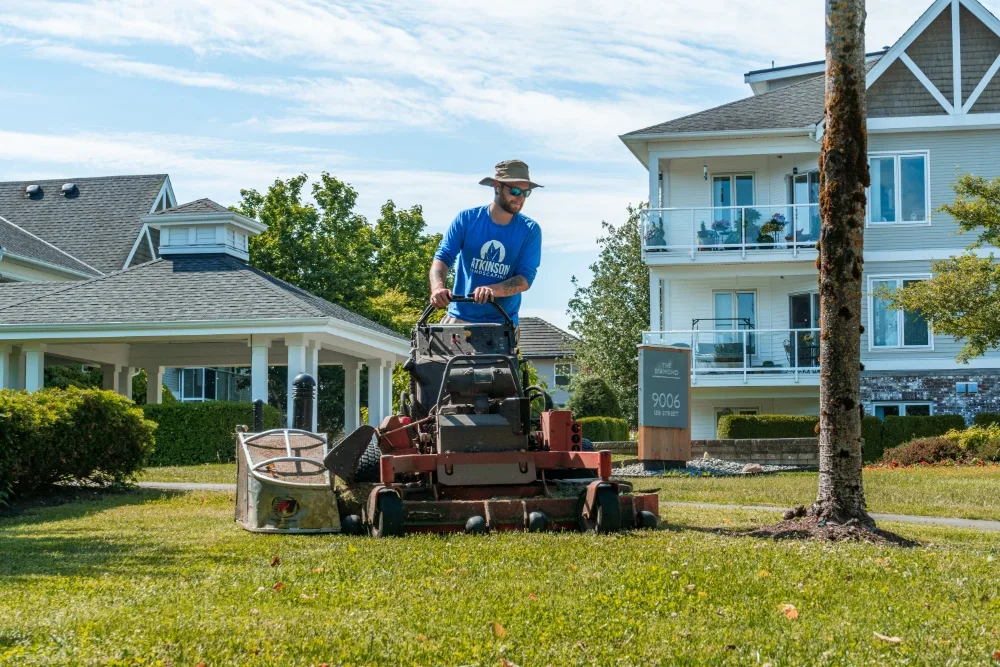 atkinson-landscaping-strata-mowing atkinson staff on a ride on mower cutting grass around a tree well