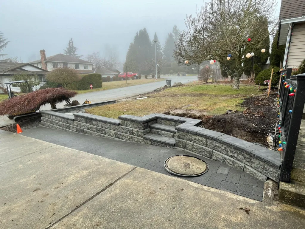 Mostly complete allan block wall along driveway with a driveway paving extension up to the base of the wall