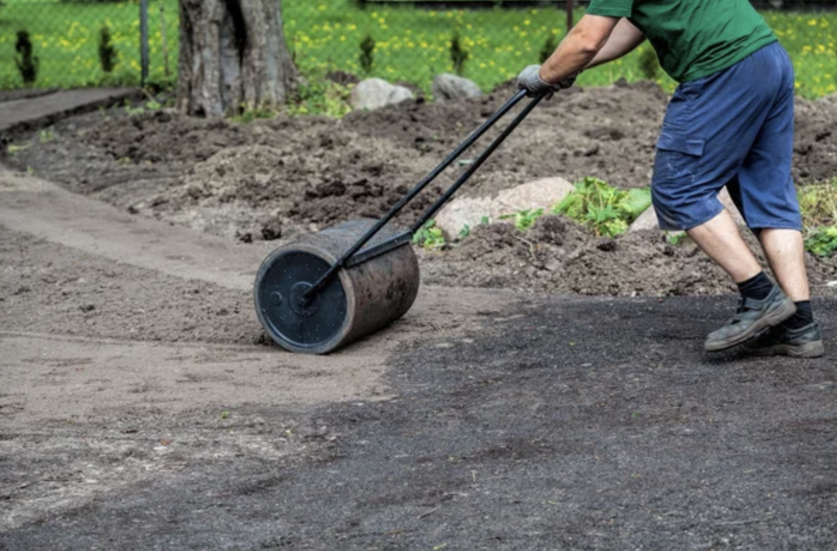 Atkinson Landscaping lawn roller a man using a lawn roller to roll fresh soil